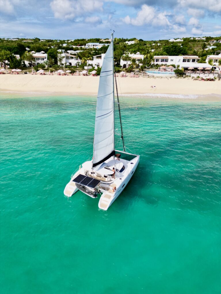 Le catamaran Respire voile hissée devant une plage d'Anguilla